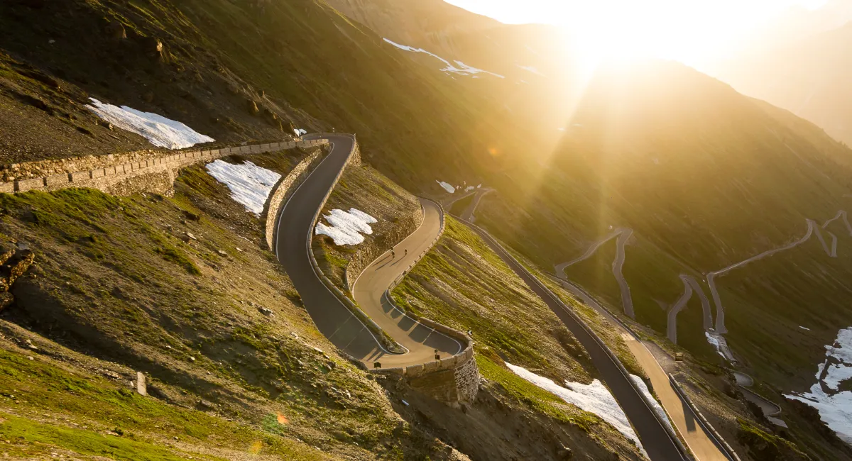 Cyclists climbing Stelvio Pass at sunrise