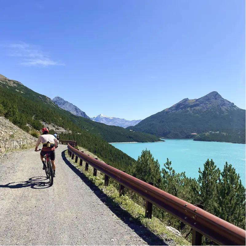 E-bikers riding along the turquoise Cancano Lake surrounded by alpine peaks