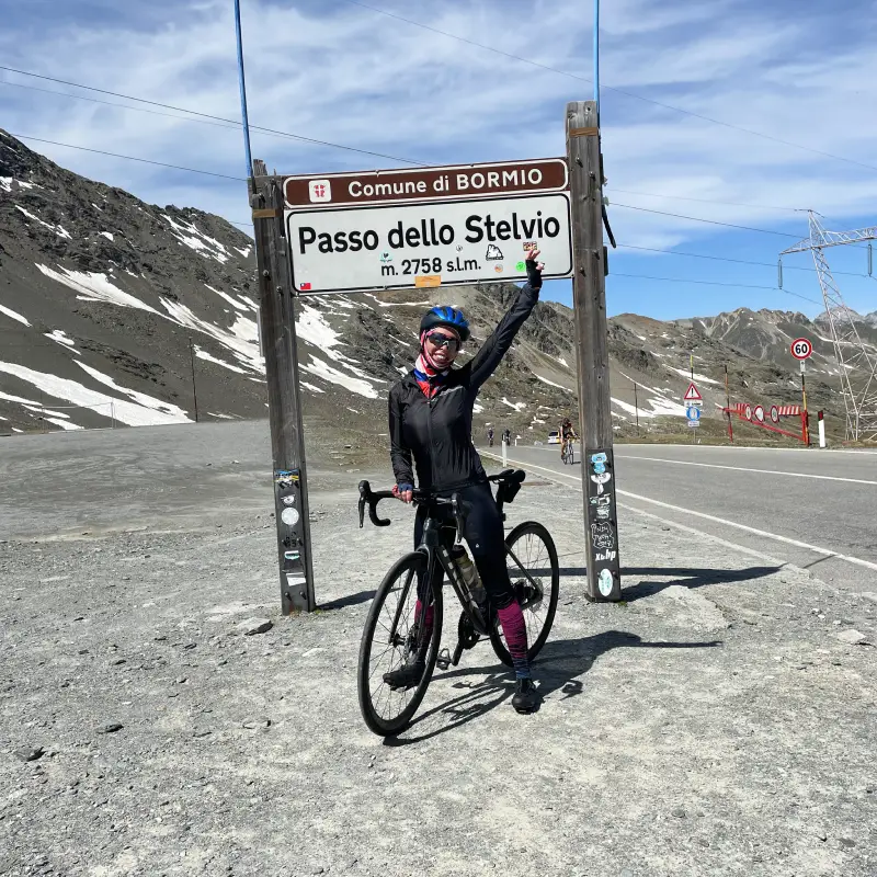 Cyclist celebrating at the Passo dello Stelvio summit after conquering the legendary climb