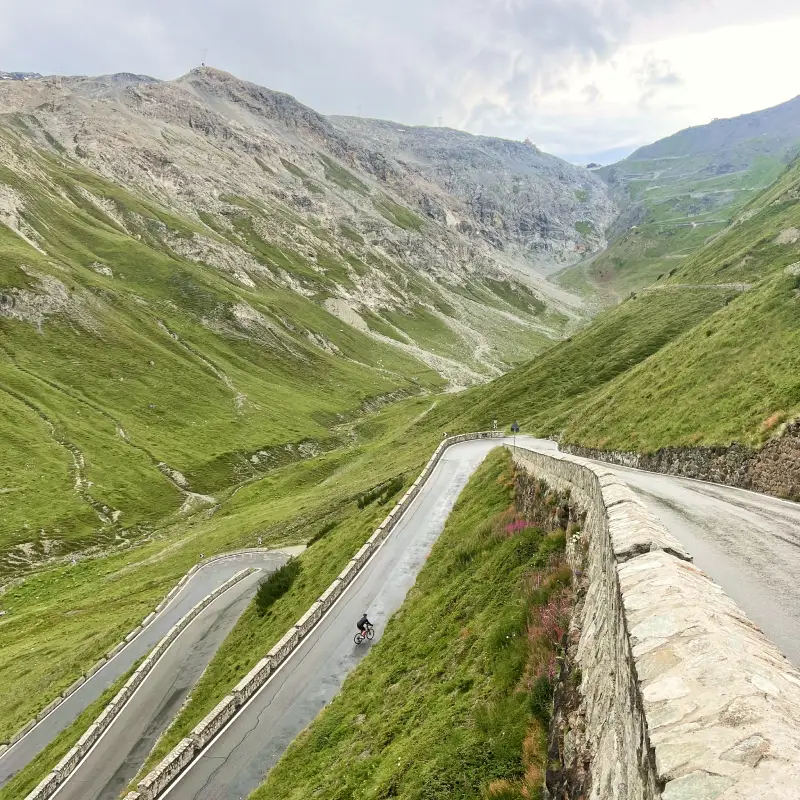 Cyclist climbing the iconic hairpins of Passo Stelvio, one of the greatest alpine roads in the world