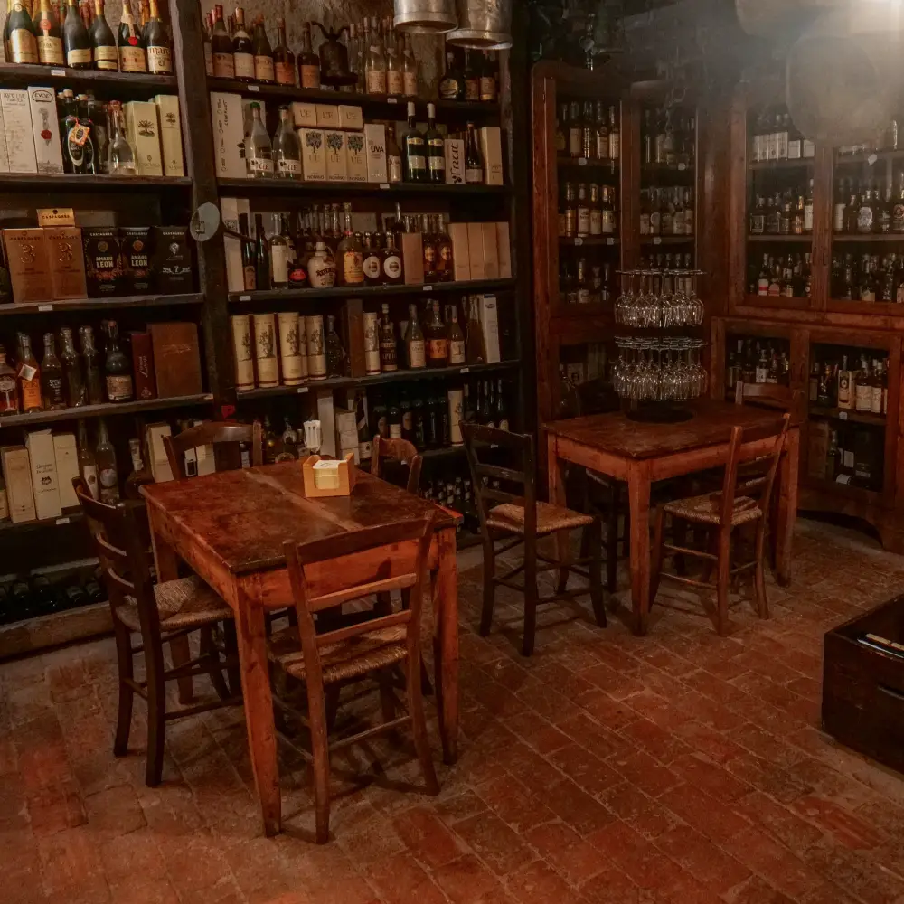 Cozy wine cellar of Da Gigetto restaurant in Follina, Veneto, with wooden tables and vintage bottles lining the shelves