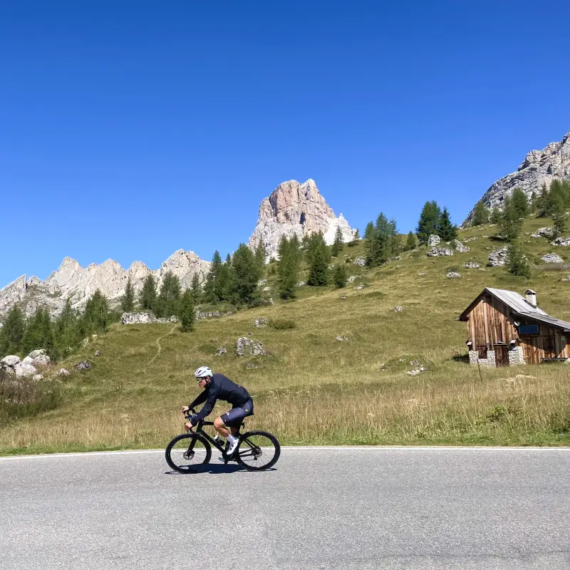 Cyclist descending from Passo Giau surrounded by Dolomites peaks