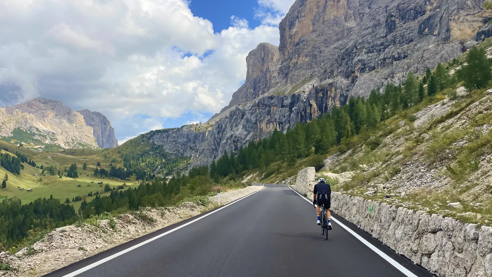 Cyclist riding through the dramatic Dolomites near Passo Gardena — the perfect introduction to the Stelvio and Dolomites Bike Tour