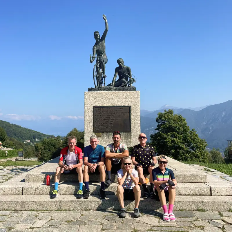 Group of cyclists resting at the Madonna del Ghisallo monument on the Stelvio to Lake Como Bike Tour
