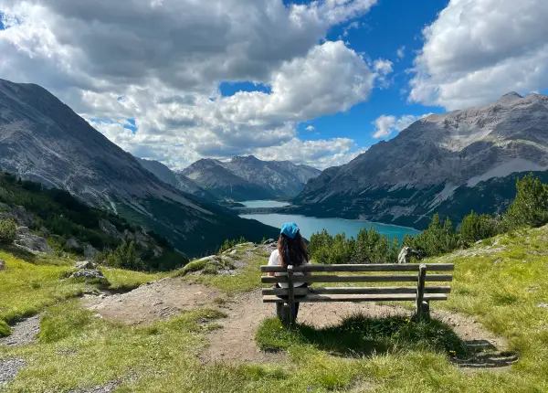 Hiker sitting on a bench overlooking the turquoise Cancano Lakes during the Monte Scale hike on the E-bike the Alps tour