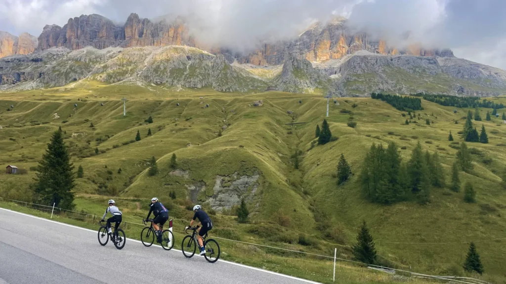 Cyclists riding up Passo Pordoi surrounded by the dramatic Dolomites peaks