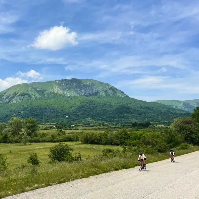 Two cyclists riding through the green valleys of Sirente Velino National Park in Abruzzo