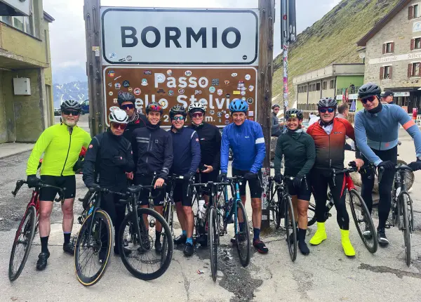 Group of cyclists celebrating at the Stelvio Pass summit on the Stelvio to Lake Como Bike Tour