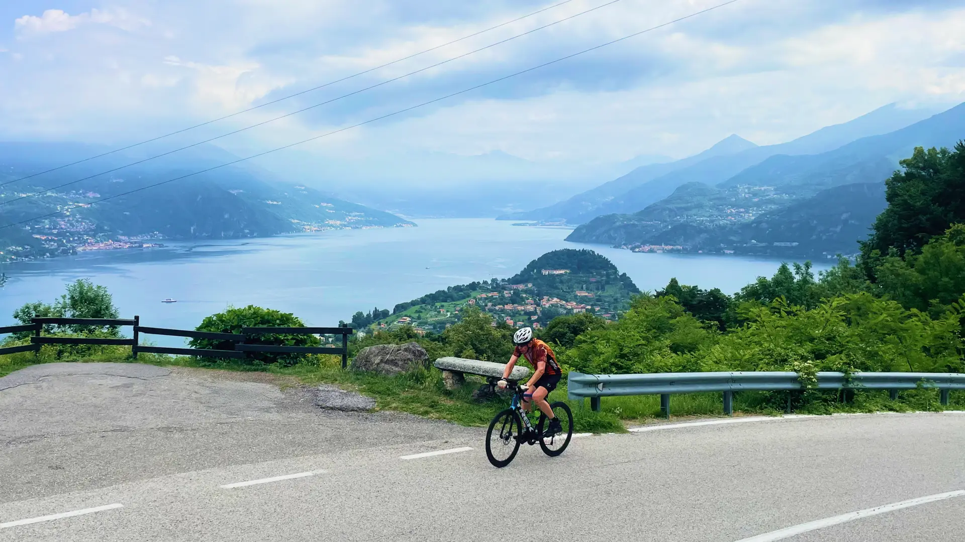 Cyclist climbing with a panoramic view over Lake Como during the Stelvio to Lake Como Bike Tour
