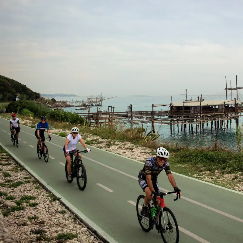 Group of cyclists riding along the Via Verde bike path by the Trabocchi Coast on the Adriatic Sea