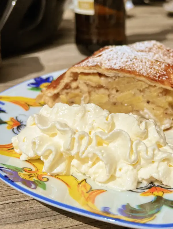 Traditional apple strudel with whipped cream, a classic reward for cyclists in the Dolomites
