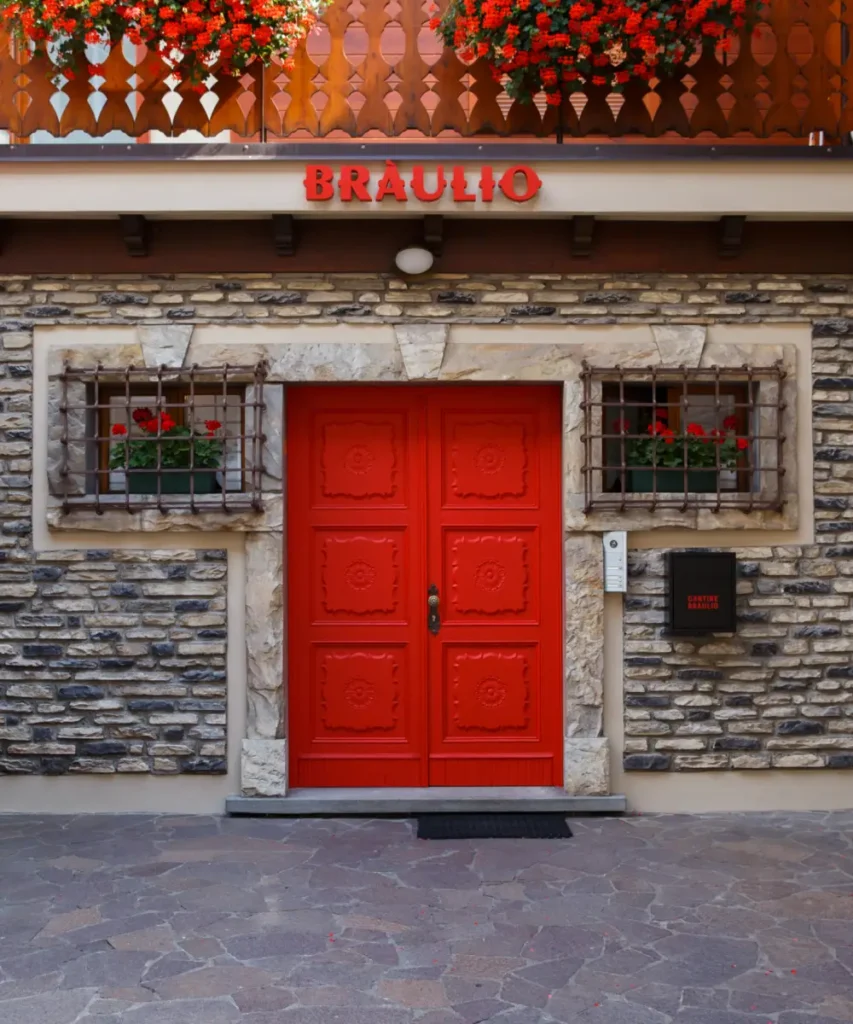 Iconic red door of the Braulio distillery in Bormio with flowers above the entrance