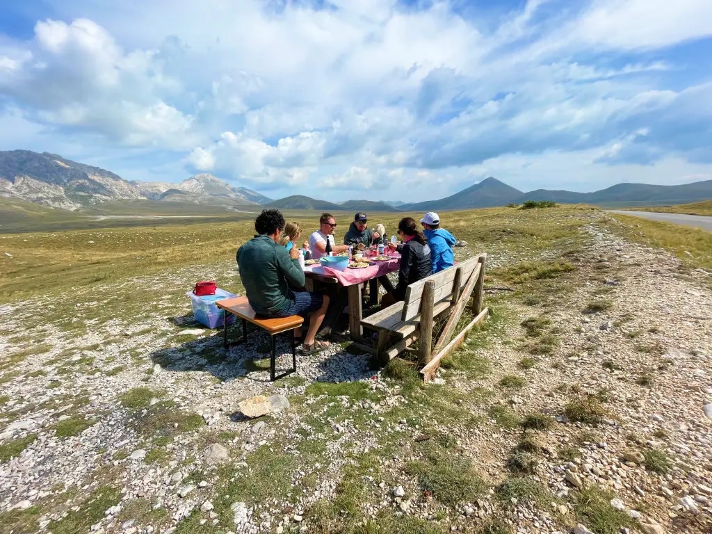 Vago Cycling group enjoying a homemade picnic on the Campo Imperatore plateau surrounded by mountains