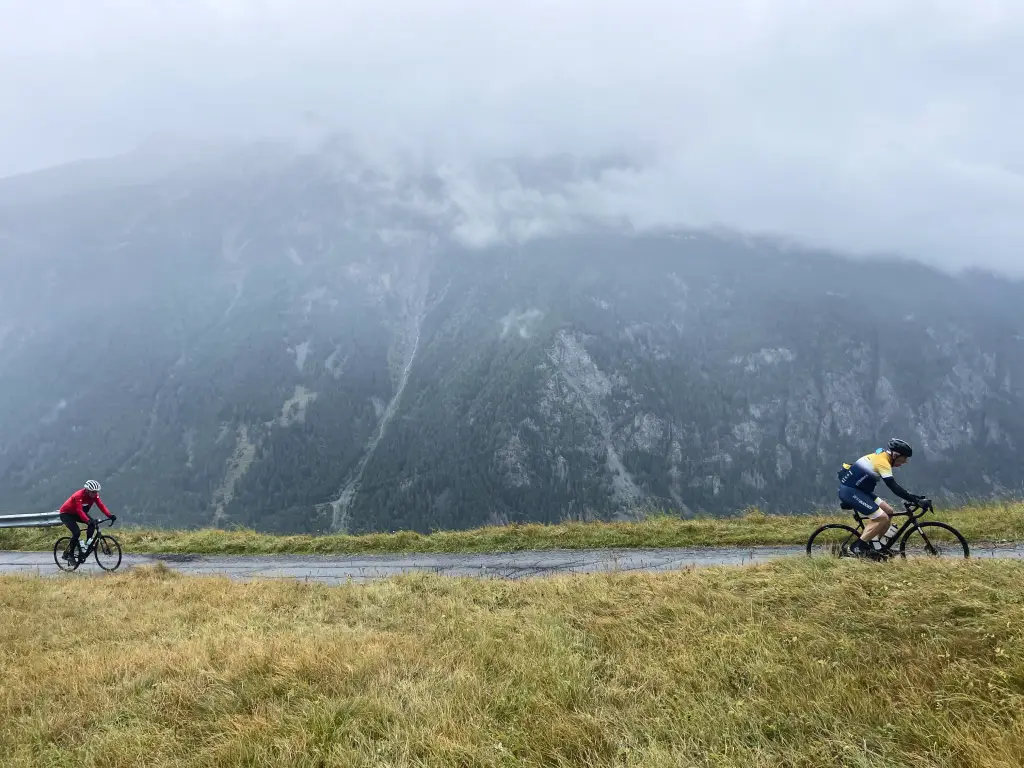 Cyclists climbing the misty road to Monte Valdisotto with dramatic mountain views