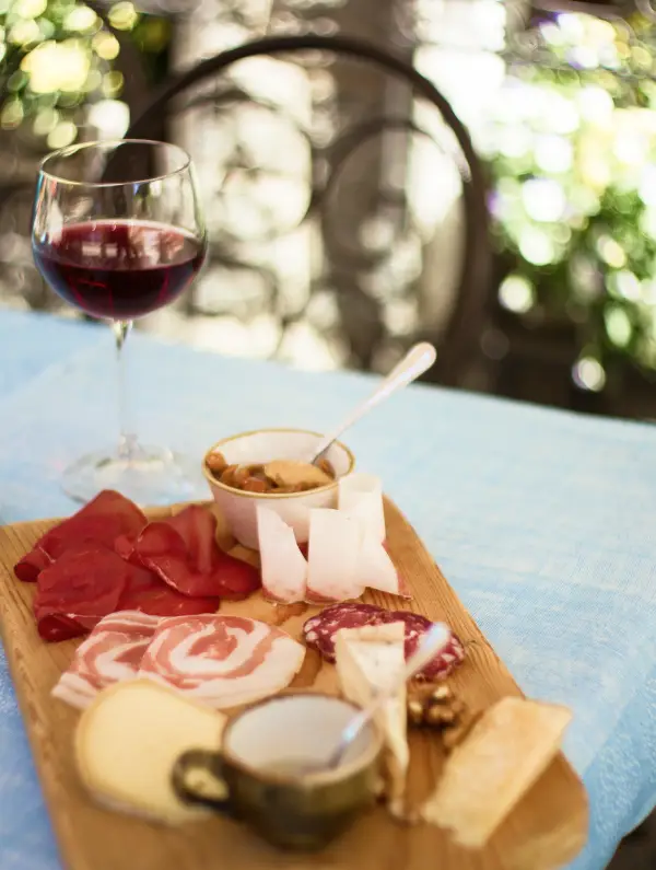 Local cured meats, cheese and a glass of red wine served outdoors, Italian aperitivo after a day of cycling in the Dolomites