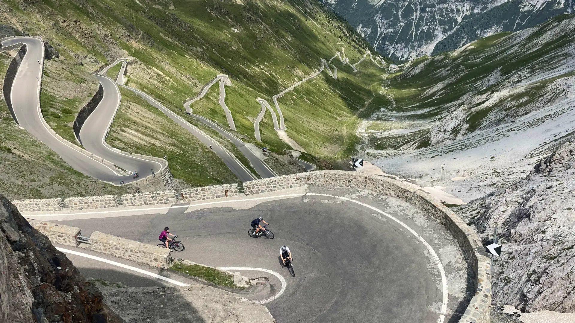 Cyclists riding the legendary Stelvio Pass with its dramatic switchbacks and alpine views on the Epic Alps bike tour