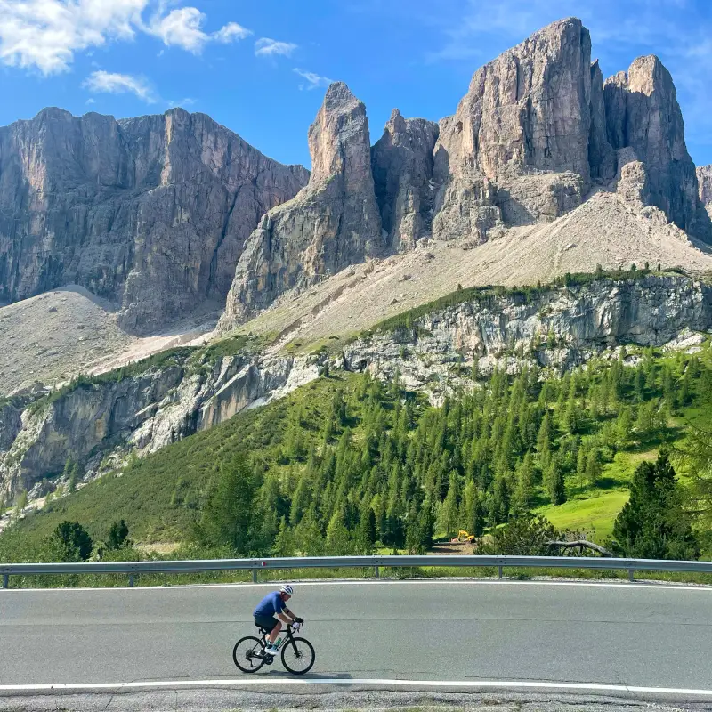 Solo rider on the Gardena Pass beneath towering Dolomite rock formations