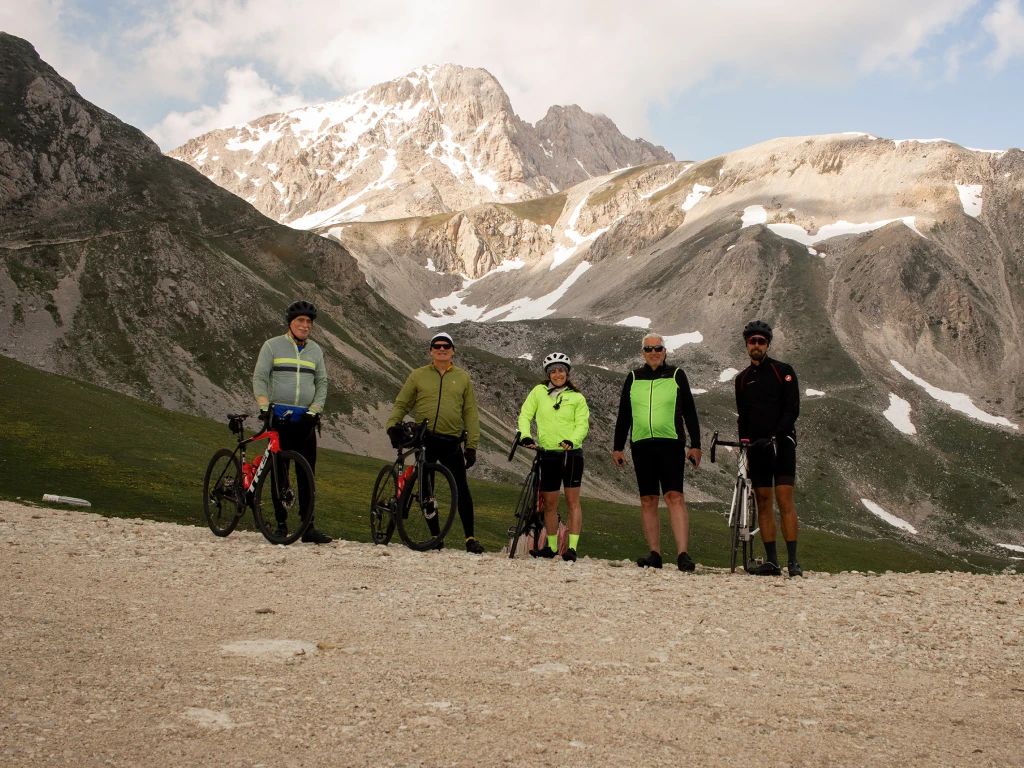 Cyclists posing at the summit of Campo Imperatore with the snow-capped Gran Sasso in the background