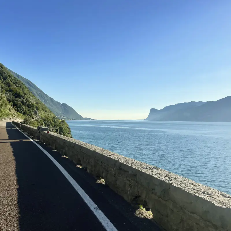 Cycling along the scenic coastal road of Lake Garda with blue water and mountains in the background