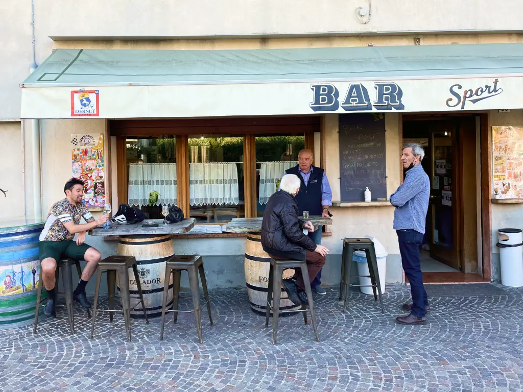 Cyclist enjoying a glass of Prosecco at a traditional local bar in a small Veneto village