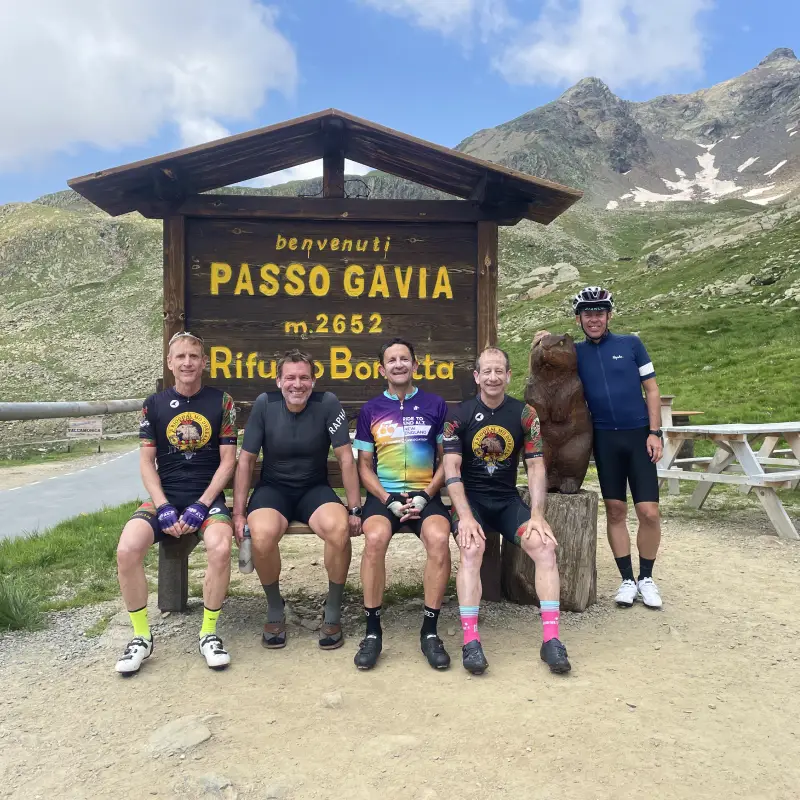 Cycling group celebrating at the top of Passo Gavia near Rifugio Bonetta after a challenging ride in the Italian Alps