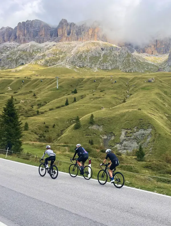 Cyclists climbing the scenic Passo Pordoi surrounded by the dramatic Dolomites landscape