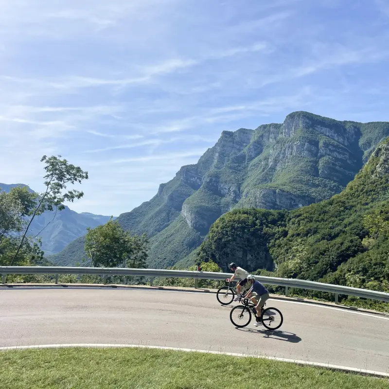 Two cyclists tackling a steep hairpin on Passo San Valentino with dramatic Trentino mountain views
