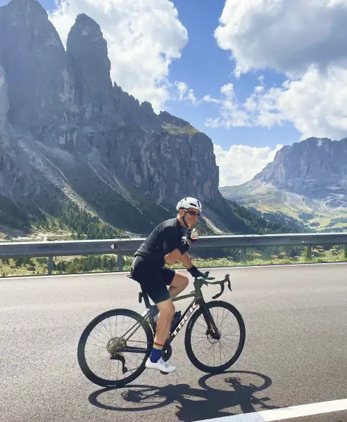 Cyclist riding a road bike through the Dolomites with dramatic mountain peaks in the background